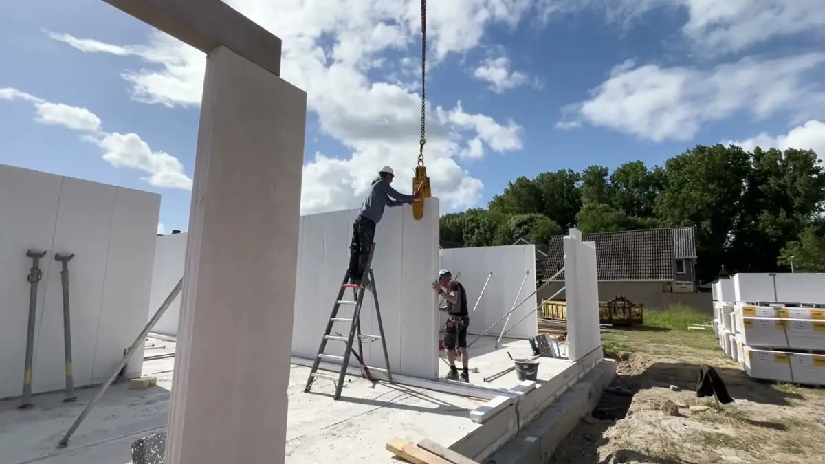 Panneau porteur en béton cellulaire descendu à la grue entre deux murs déjà réglés